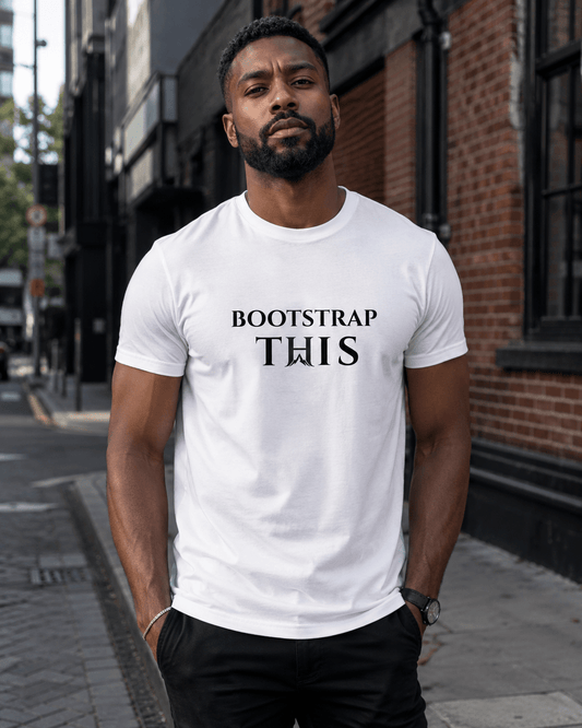 Man wearing the White Bootstrap This Men’s Tee — Black Edition with black artwork on a brick-lined city street