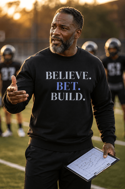 Black Bootstrappin’ BELIEVE. BET. BUILD. crewneck — model on a sports field