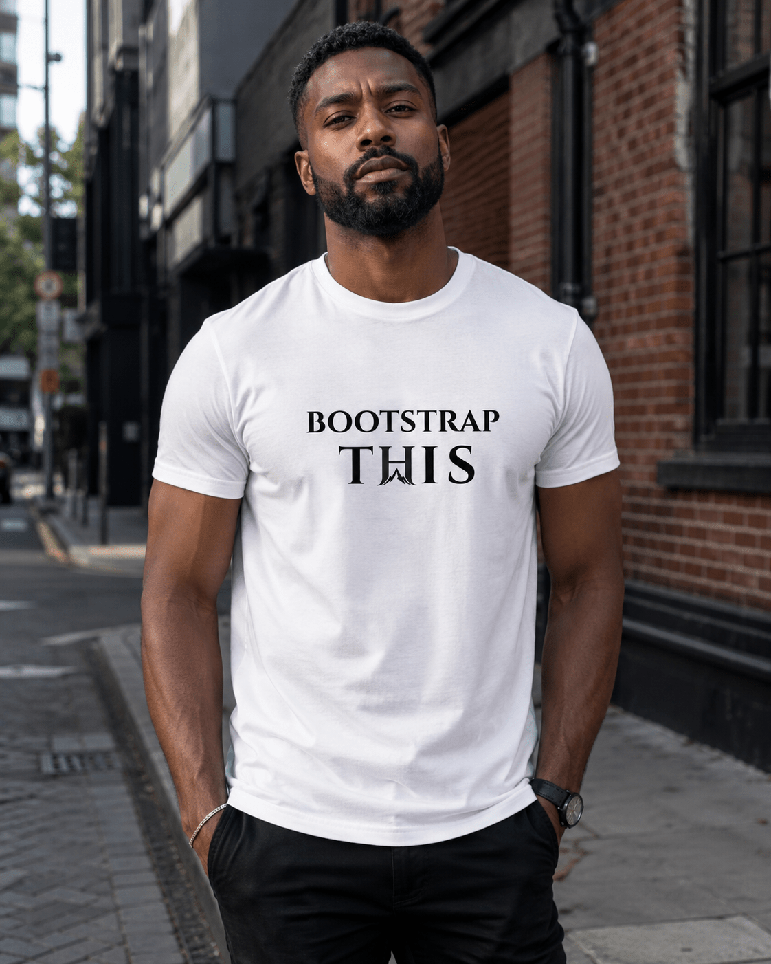 Man wearing the White Bootstrap This Men’s Tee — Black Edition with black artwork on a brick-lined city street