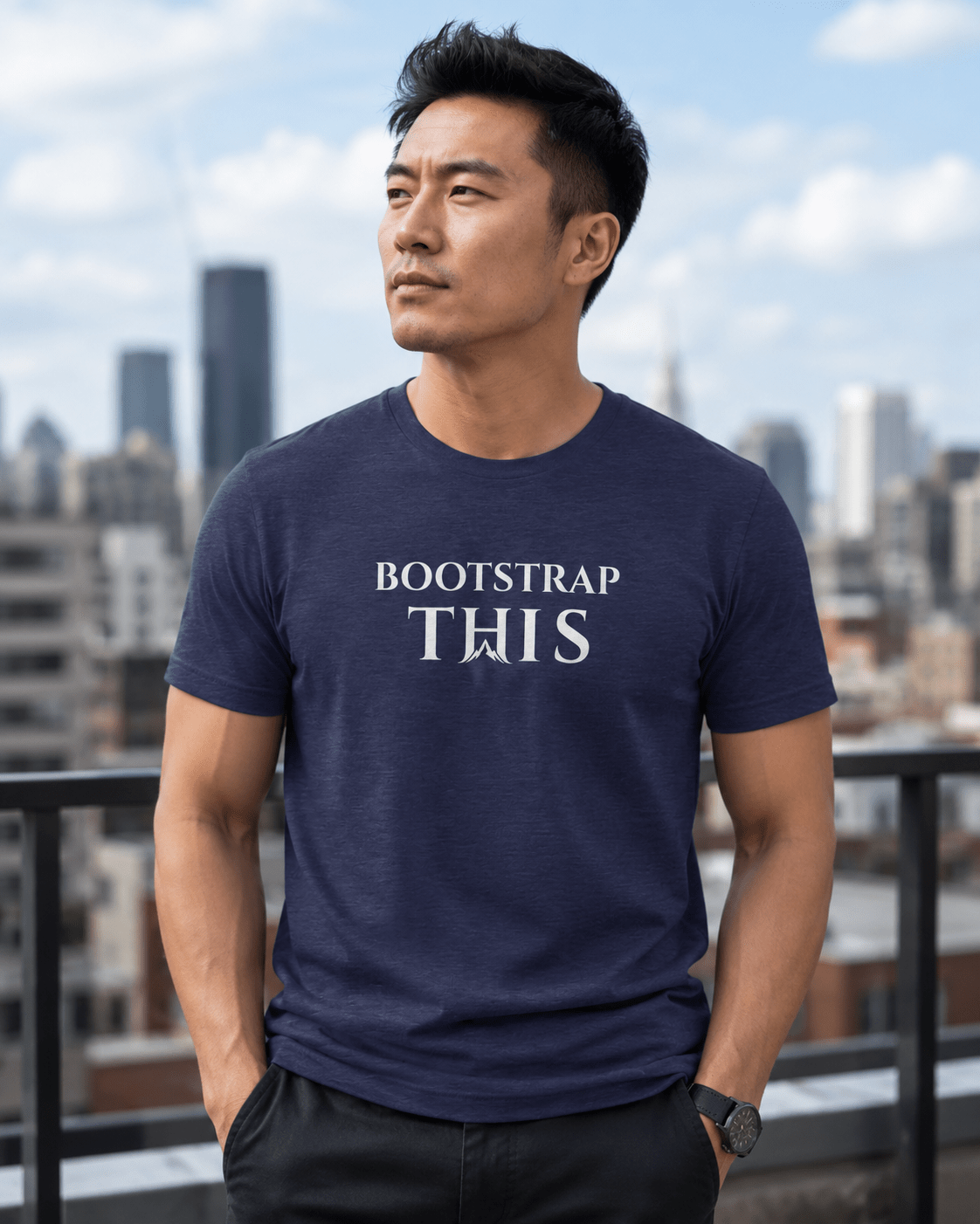 Man wearing the Heather Midnight Navy Bootstrap This Men’s Tee — White Edition with white artwork on a city rooftop