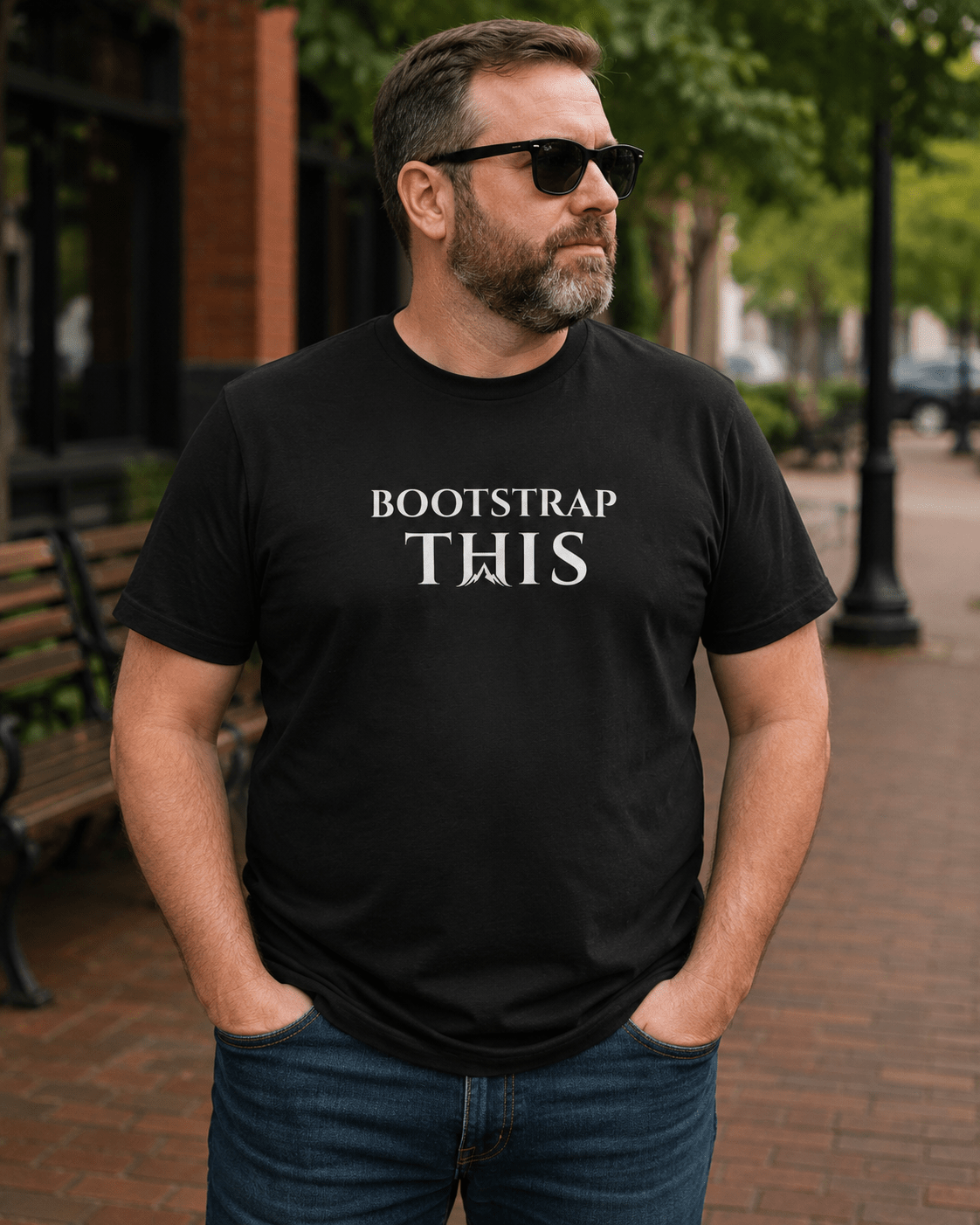 Man wearing the Vintage Black Bootstrap This Men’s Tee — White Edition with white artwork on a brick sidewalk