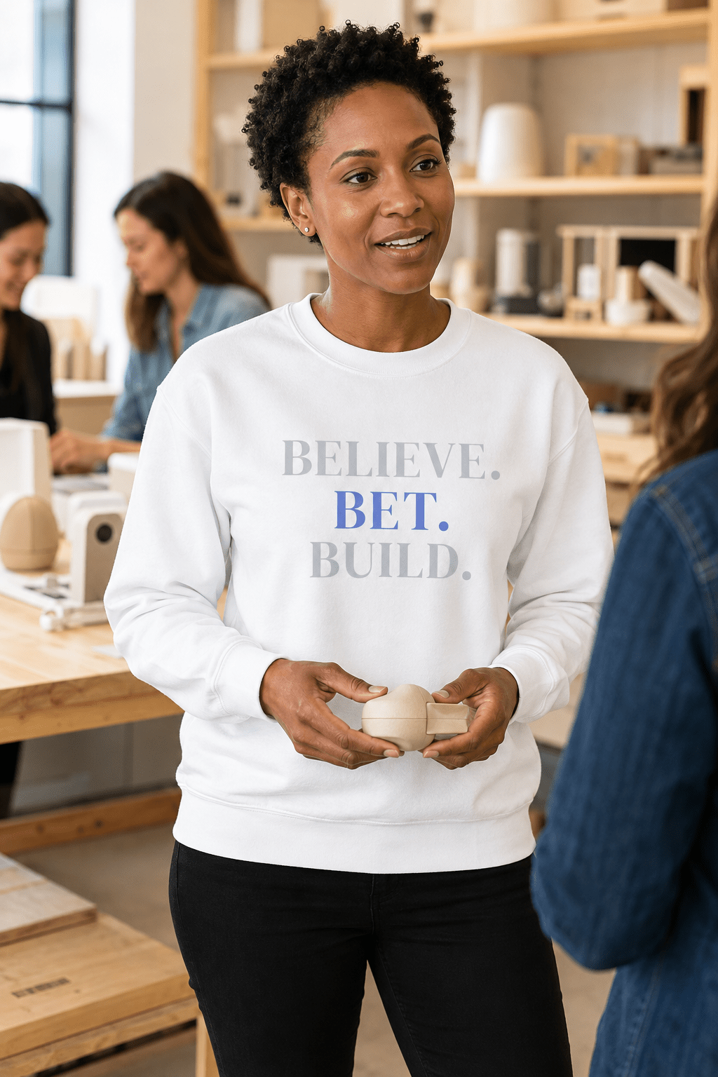 White Bootstrappin’ BELIEVE. BET. BUILD. crewneck — model in a cafe