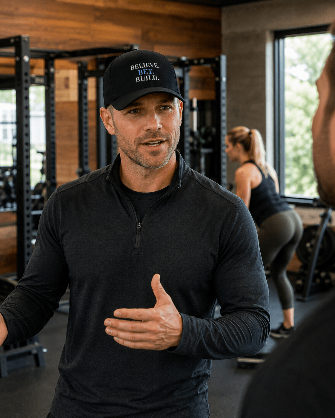 Black Bootstrappin’ BELIEVE. BET. BUILD. Flexfit cap — model indoors