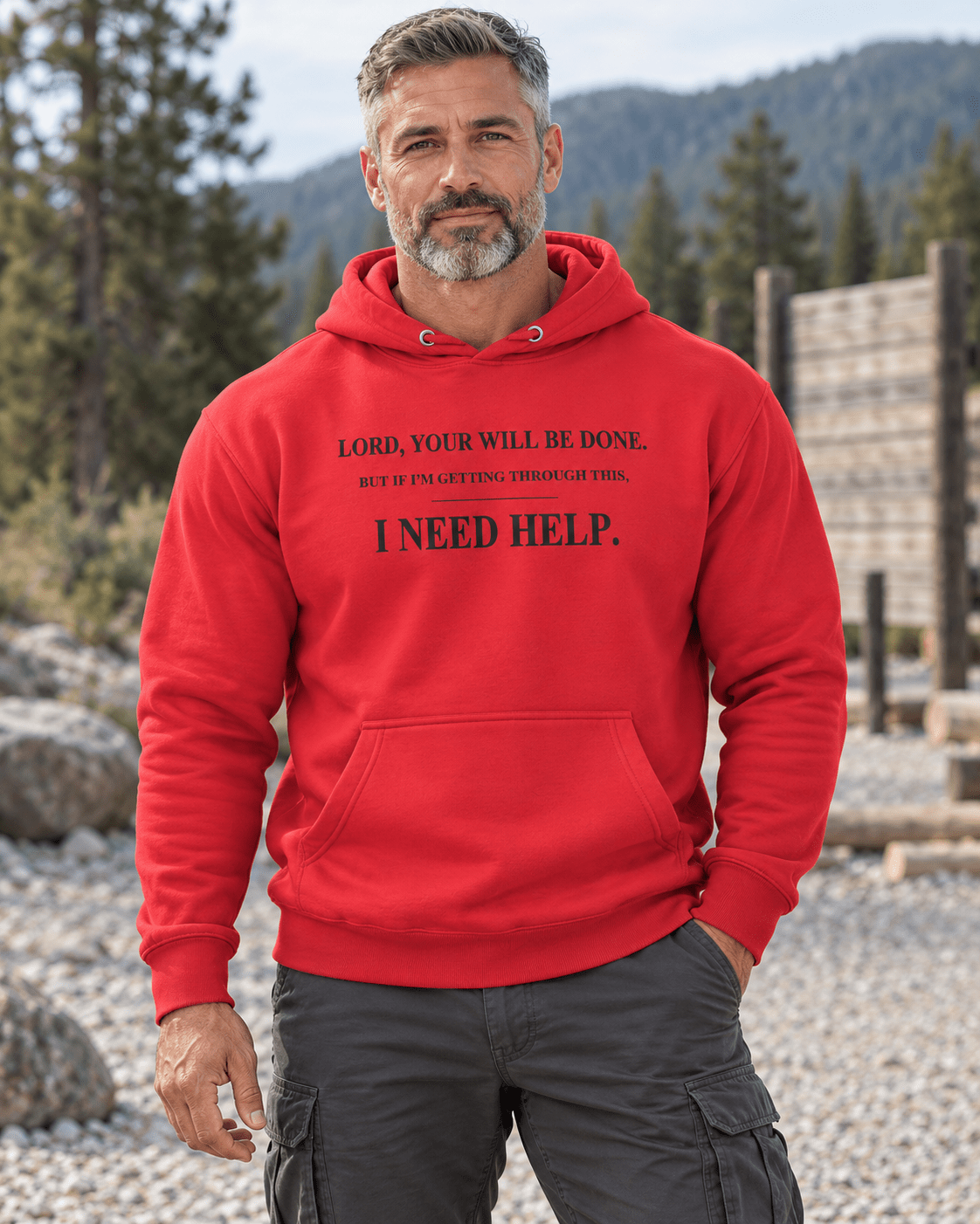 Man at a rugged trailhead wearing a Team Red DESCENT faith hoodie, front view showing Your Will Be Done and I Need Help lettering