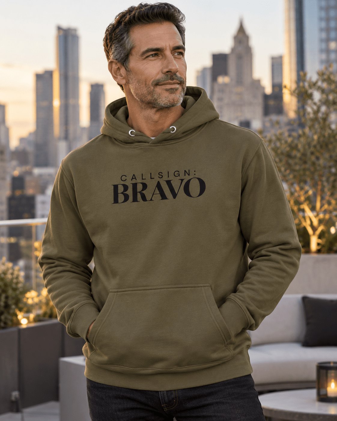 Man wearing a Military Green God Is Good CALLSIGN: BRAVO hoodie on a rooftop terrace — front view