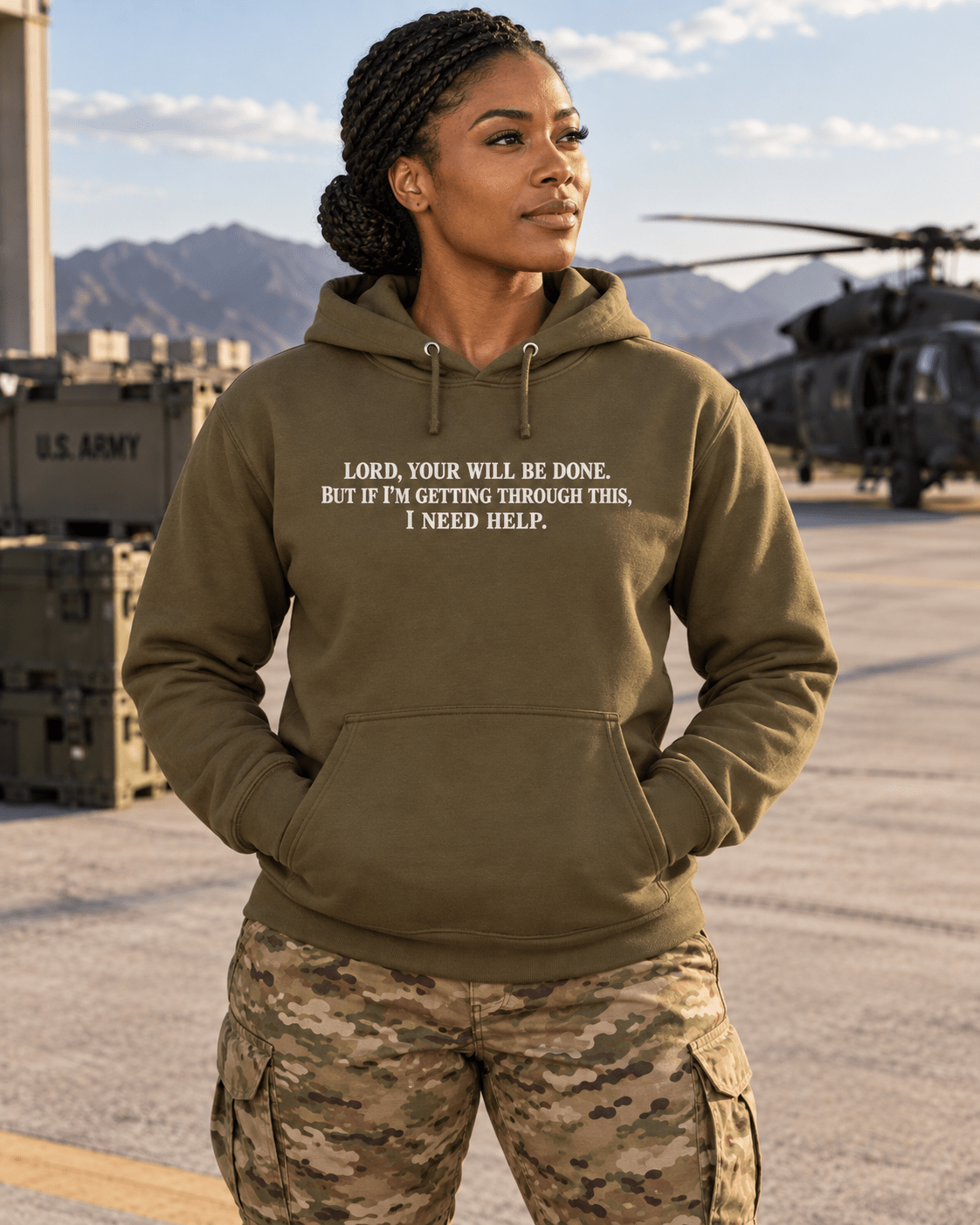 Woman wearing a Military Green Your Will Be Done: Descent CALLSIGN: BRAVO hoodie beside a helicopter on an airfield — front view