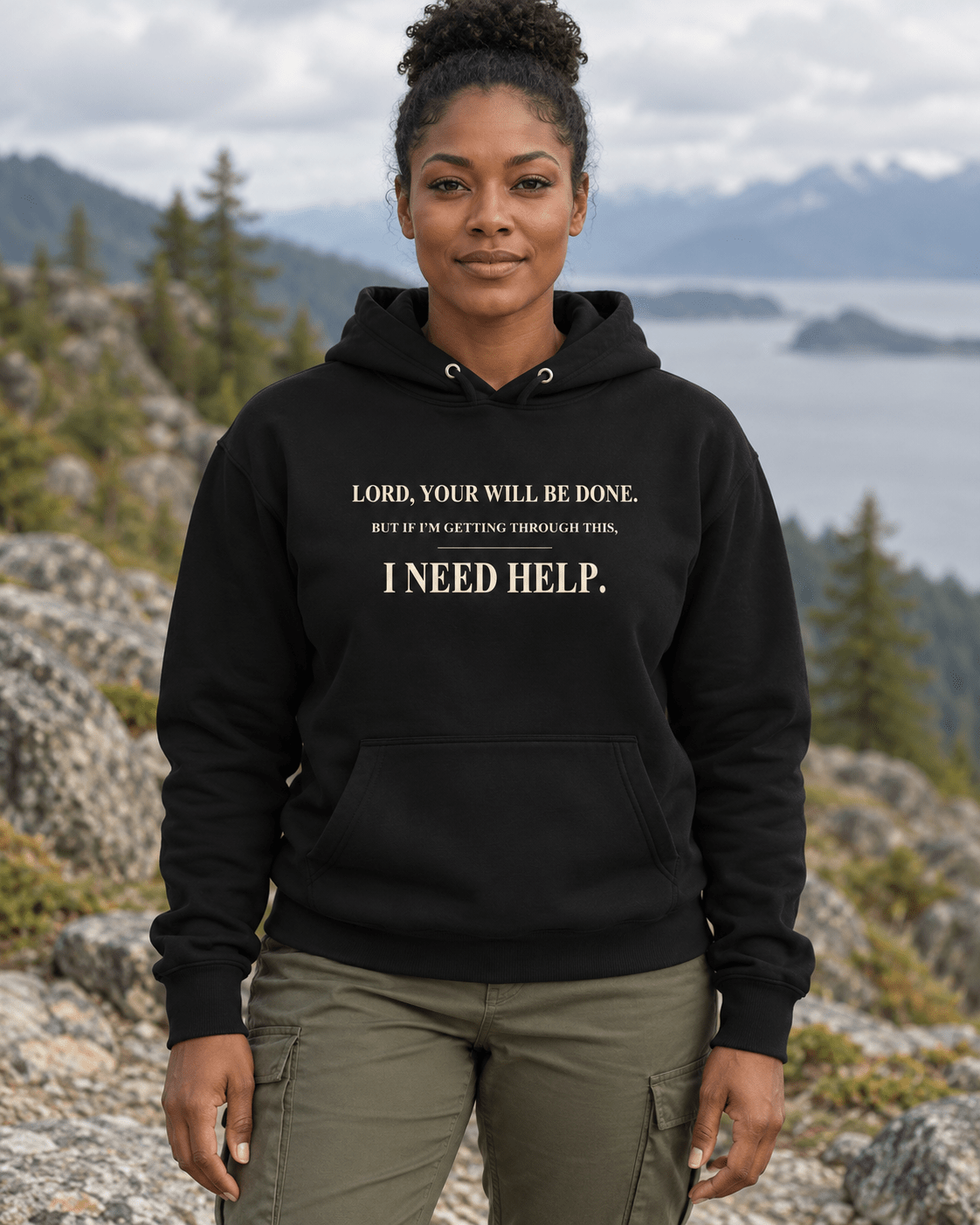 Woman outdoors wearing a Black DESCENT faith hoodie, front view showing Your Will Be Done and I Need Help lettering